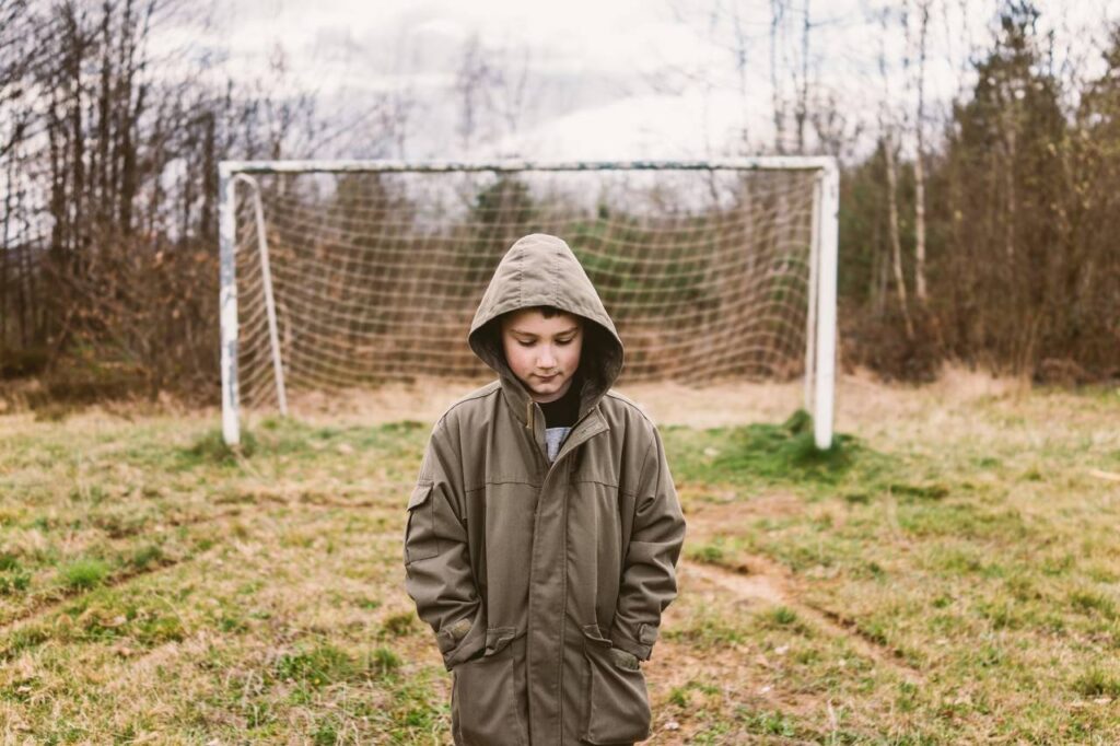 Menino em um campo de futebol sozinho