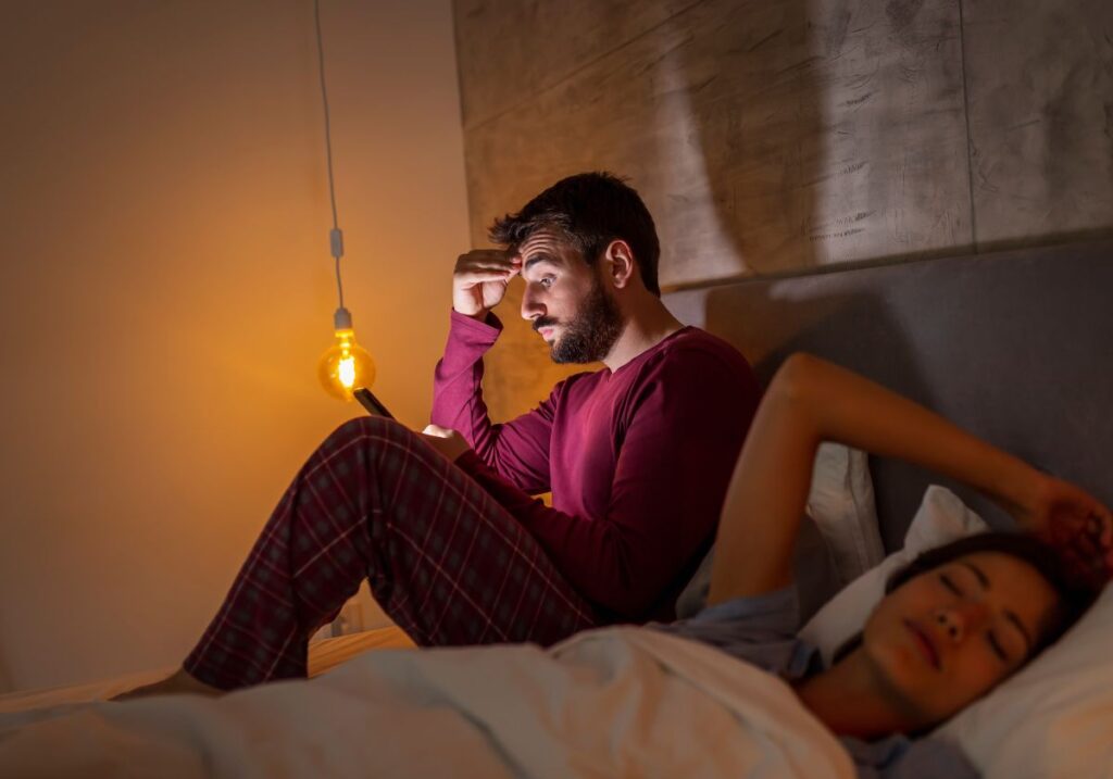 Pessoa mexendo no celular na cama
